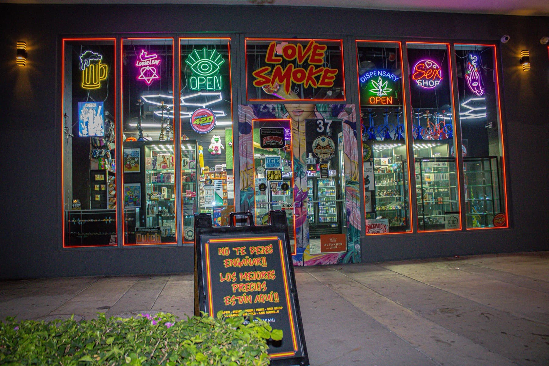Love Smoke Miami at night — a black storefront lit by a wall of neon signs on NE 15th Street in downtown Miami